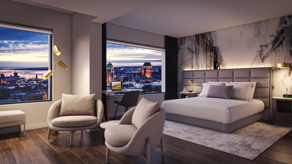 Night-time photograph of a room at the Hilton Québec with a double bed and lounge area. The room offers a view of the St. Lawrence River and Quebec City's illuminated downtown skyline.