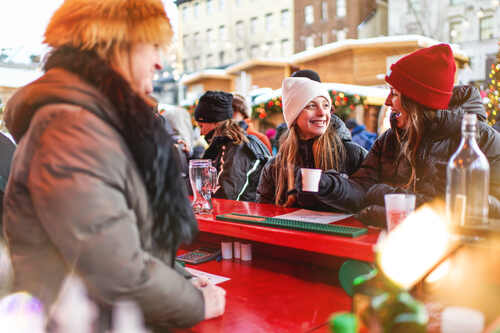 Artisan vendant du vin chaud à des visiteurs à son kiosque du Marché de Noël allemand de Québec.