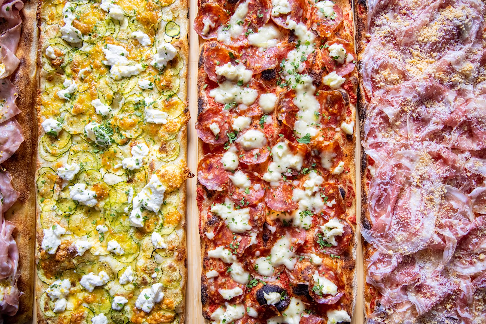 Quatre pizzas romaines croustillantes et colorées, disposées les unes à côté des autres